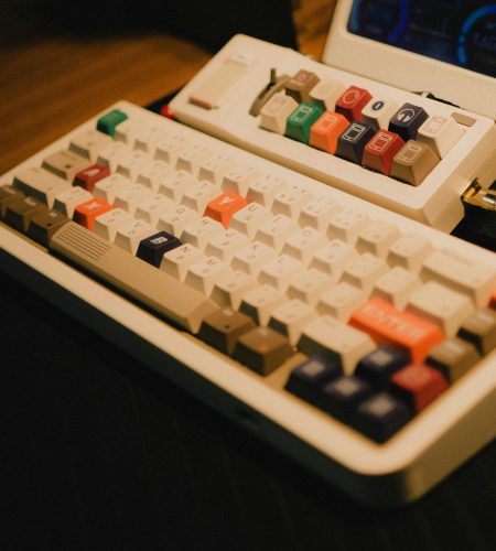 Vintage mechanical keyboard with colorful keys on a wooden desk, evoking a classic gaming setup.