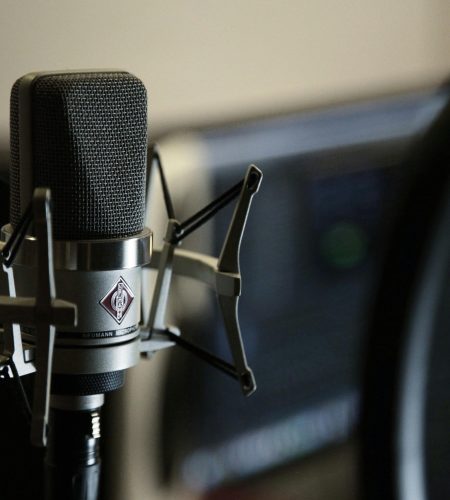 Detailed view of a condenser microphone in a recording studio setting.